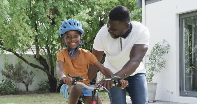 African American father teaches son to ride a bike outdoors