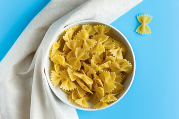 Raw pasta farfalle with copy space on blue background