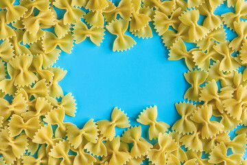 Raw pasta farfalle with copy space on blue background