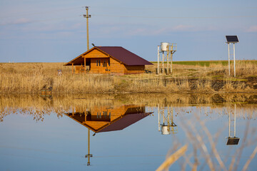 the wooden cabin that is reflected in a water.
