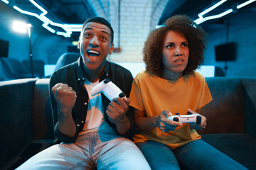 Man and woman play console and show emotions.