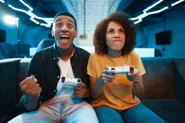 A man and a woman have fun playing a video game on the couch