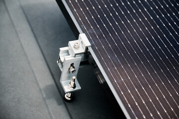 Close up of solar panel, securely fastened with robust mounting clamp to supporting structure on...