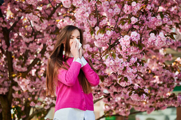 Woman allergic suffering from seasonal allergy at spring in blossoming garden at springtime. Woman...
