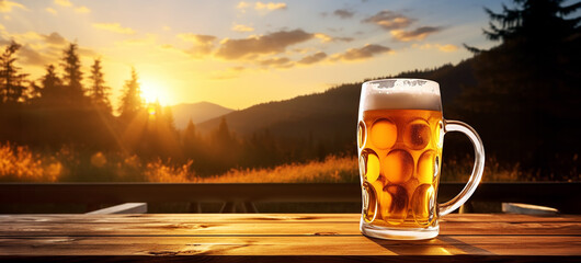 A mug full of beer and foam on a wooden table against a background of sunset scene in the mountains. - 740653369