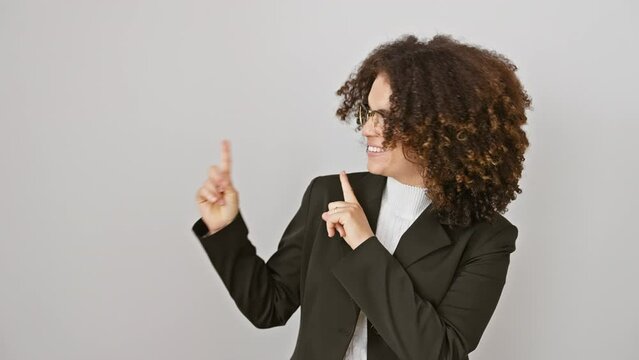 Confident hispanic woman with curly hair, cheerfully standing, pointing to the side, smiling big at the camera. both hands gesture welcome on isolated white background.