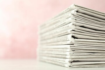Stack of newspapers on pink background, closeup. Journalist's work