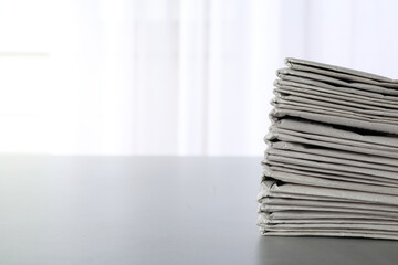 Stack of newspapers on grey table, space for text. Journalist's work