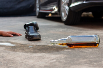 Liquor Alcohol Bottle fell on The Floor with car and shoe background.don't drink and drive concept.