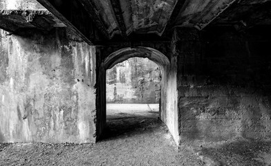Fototapeta na wymiar Eerie underpass with shabby concrete walls on an abandoned factory site of a former steelworks in Duisburg in the Ruhr Basin, Germany. Contrasting black and white greyscale in lost place location