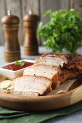 Pieces of baked pork belly served with sauce on grey wooden table