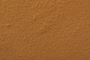 Dry aromatic cinnamon powder as background, top view