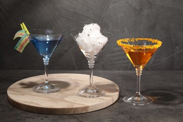 Tasty cotton candy cocktail and other alcoholic drinks in glasses on gray textured table