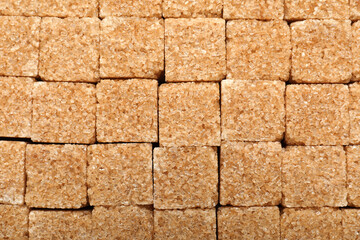 Brown sugar cubes as background, top view