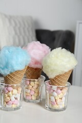 Sweet cotton candies in waffle cones and marshmallows on white table indoors
