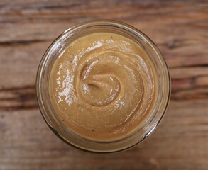 Tasty nut paste in jar on table, top view