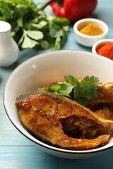 Tasty fish curry and ingredients on light blue wooden table, closeup. Indian cuisine