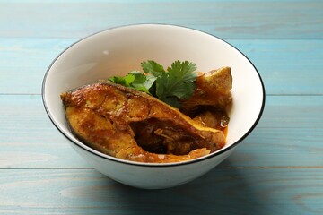 Tasty fish curry on light blue wooden table, closeup. Indian cuisine