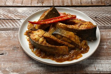 Tasty Indian fish curry on wooden table, closeup