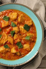 Delicious chicken curry on wooden table, top view