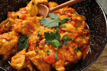 Delicious chicken curry in bowl and spoon on table, closeup
