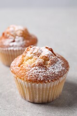 Delicious sweet muffins on light grey textured table, closeup. Space for text