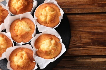 Delicious sweet muffins on wooden table, top view. Space for text