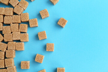 Brown sugar cubes on light blue background, top view. Space for text