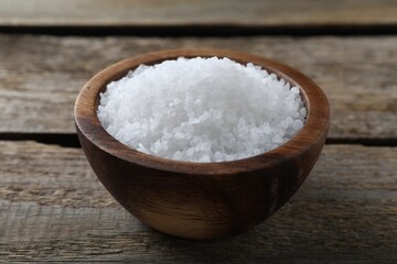 Fototapeta na wymiar Organic salt in bowl on wooden table, closeup