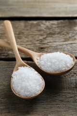 Organic salt in spoons on wooden table, closeup