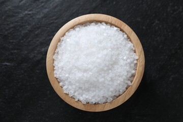 Fototapeta na wymiar Organic white salt in bowl on black table, top view