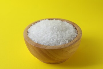 Organic white salt in bowl on yellow background