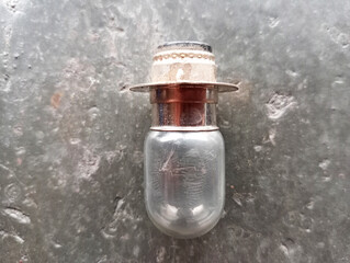 Broken motorcycle headlight bulb on the floor. This motorbike light bulb is used on the front.