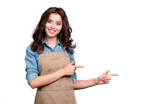 Nice cute stylish positive lovely sweet winsome attractive brunette caucasian girl, barista with wavy hair in casual denim shirt and apron, pointing two fingers aside, isolated over grey background