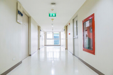 Modern and clean hospital corridor with smoke detector, fire exit sign and fire hose reel cabinet