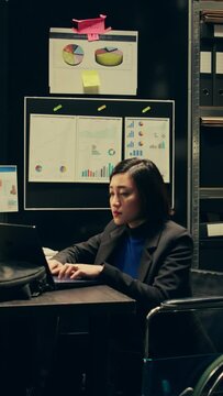 Vertical Video Forensic team extracting DNA samples for modern analysis in archive room, examining criminal evidence and compiles statistical data. Agent with disability working on private