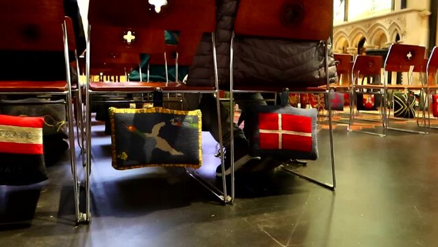 Cute embroidered cushions used to kneel and pray hanging from chairs