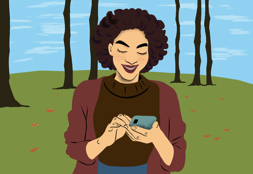 Smiling woman using smartphone in autumn park