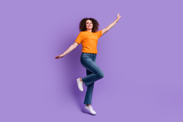 Fototapeta na wymiar Photo of joyful cheerful woman wear orange clothes jump up fly air travel isolated on purple color background
