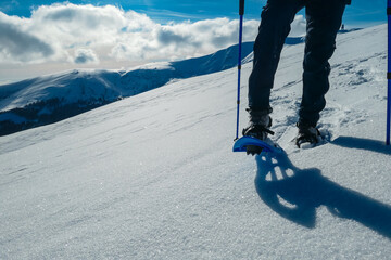 Close up view of person wearing snow shoes and walking in white fluffy snow on alpine meadow in Kor...