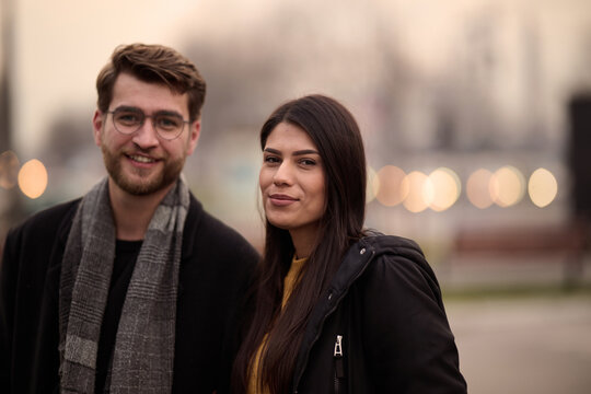 A romantic couple embraces in a tender hug as they stroll through the city streets, enjoying leisure time together in each other's company
