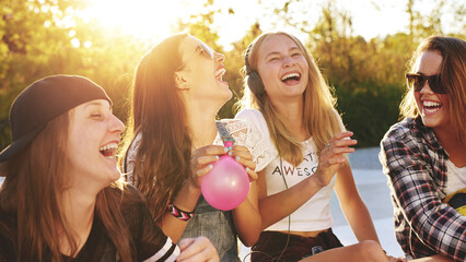 Portrait of best friends laughing together while blowing up balloons - 740676931