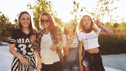 Group of girls laughing while they dance outdoors in the sunset - 740676984