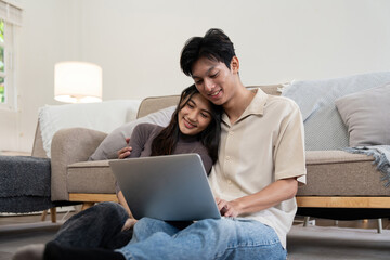 Fototapeta premium Happy couple asian with laptop on floor in the living room at home