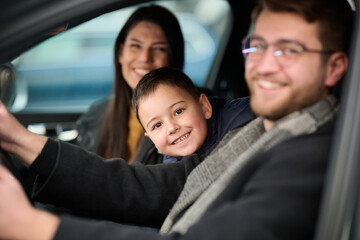 In the nighttime hours, a happy family enjoys playful moments together inside a car as they journey on a nocturnal road trip, illuminated by the glow of headlights and filled with laughter and joy