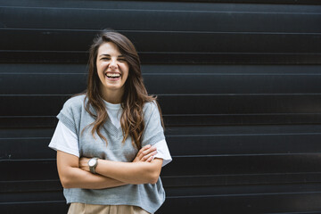 Portrait of young confident successful business woman standing outside office building. Educated independent female team leader businessperson posing against black wall.