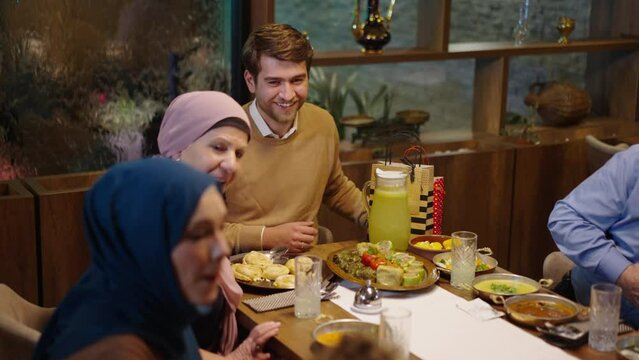 Young Muslim Parents and Grandmother Happily Talk to a Boy at Dinner in Ramadan or on Eid