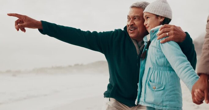 Grandfather, beach and child with point, holiday and happy for teaching in nature, bonding or holding hands. People, family and kid with senior man, hug or show direction by sea on vacation with chat