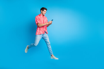 Full body photo of busy guy wear stylish shirt jeans trousers run empty space read sms on smartphone isolated on blue color background