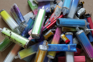 Collection of discarded vapes on a cardboard Discarded electronic cigarette vapes that have been...